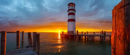 Najpiękniejsze latarnie morskie w Polsce - latarnia na tle zachodzącego słońca na tle spokojnego morza