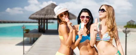 Trzy młode kobiety  cieszą się swoim towarzystwem i piękną pogodą nad morzem jedząc lody